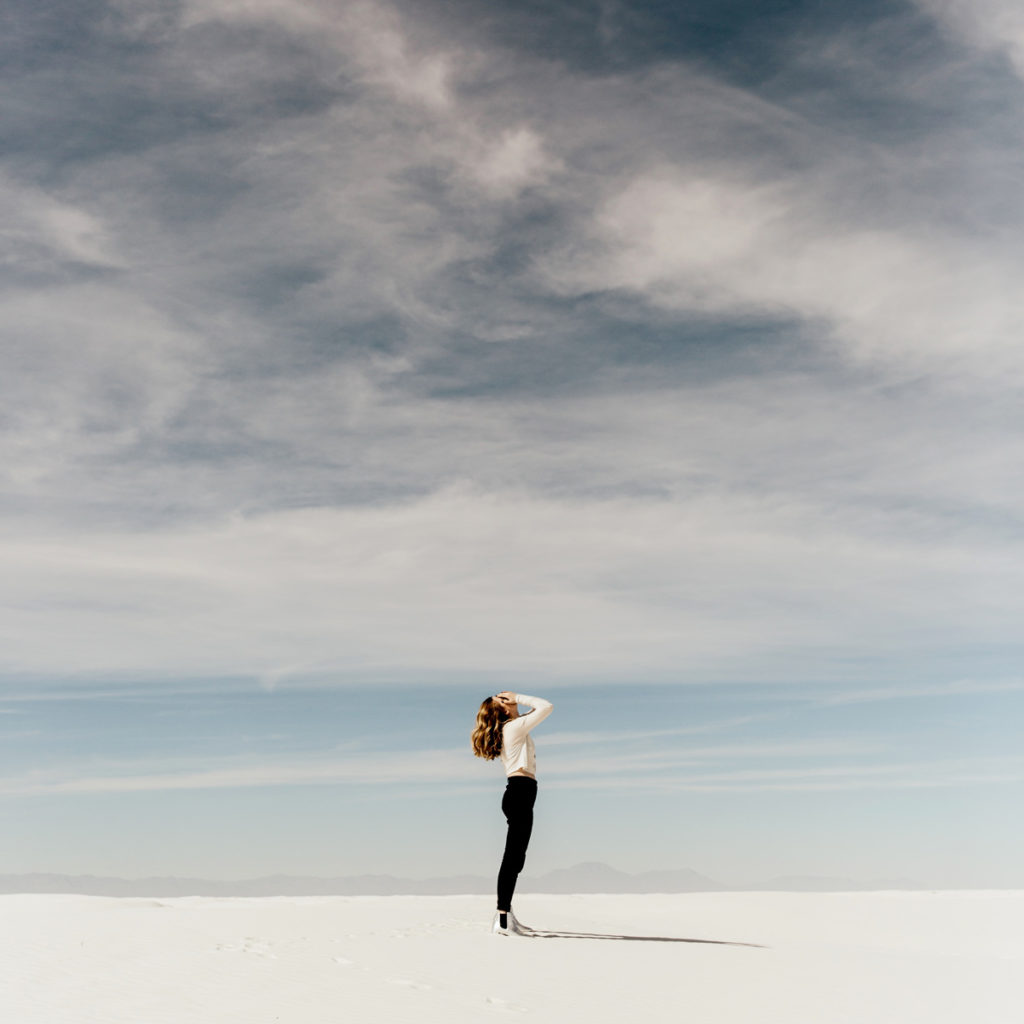 woman looking up at sky on beach